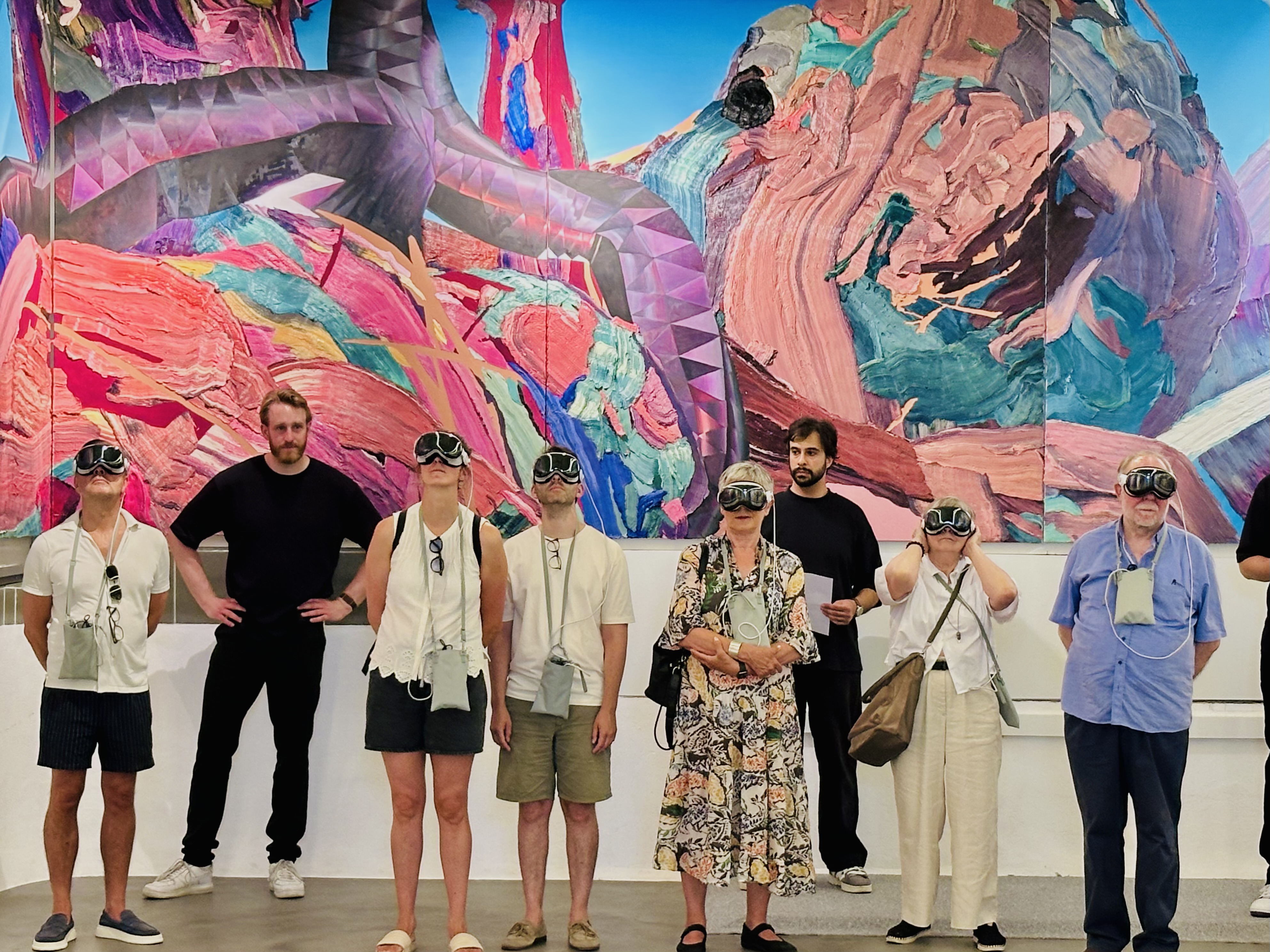 Up to fifteen visitors in Apple Vision Pro headsets before the painted frieze.