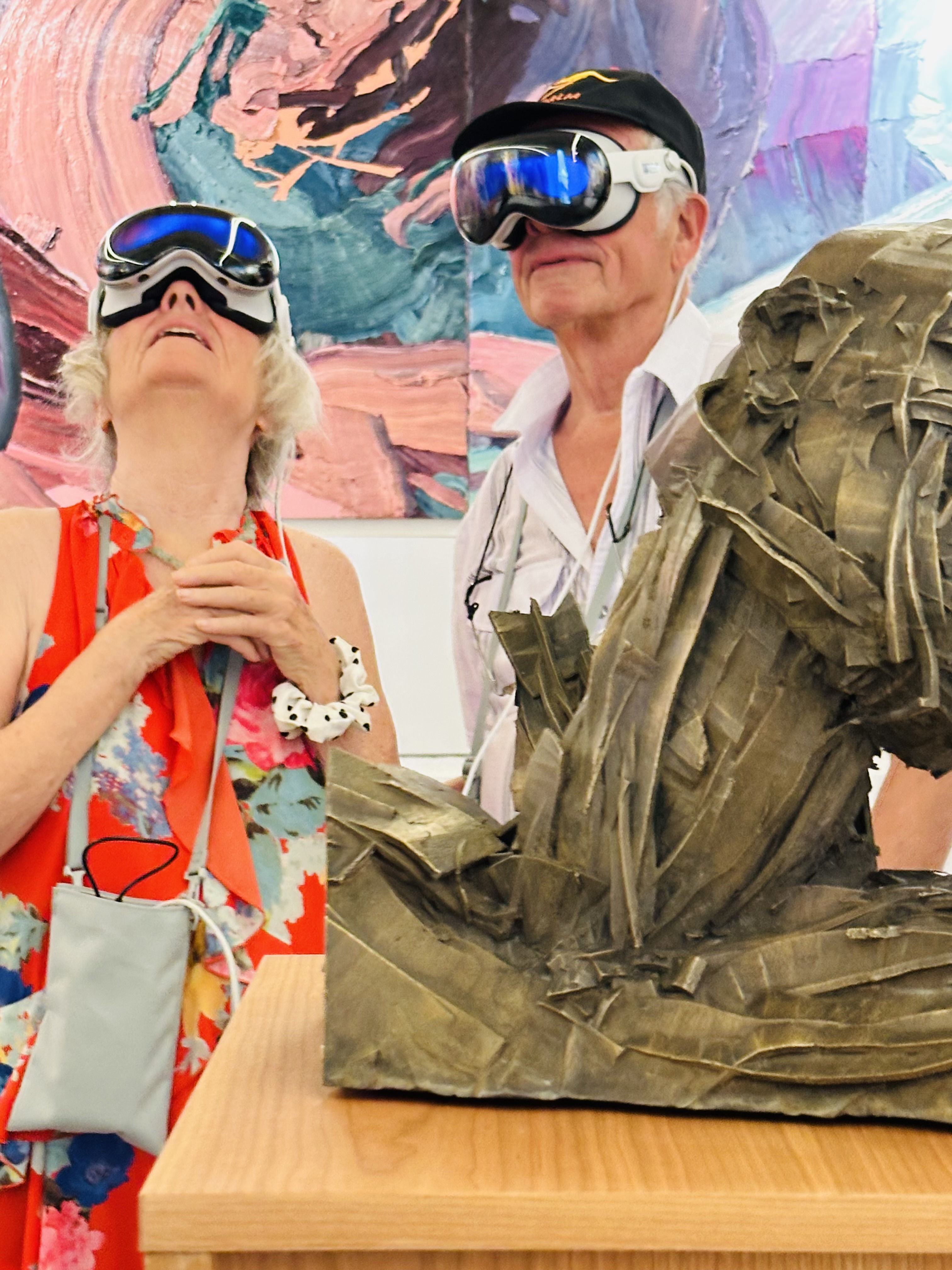 Two visitors in Apple Vision Pro before the frieze, with a bronze sculpture.